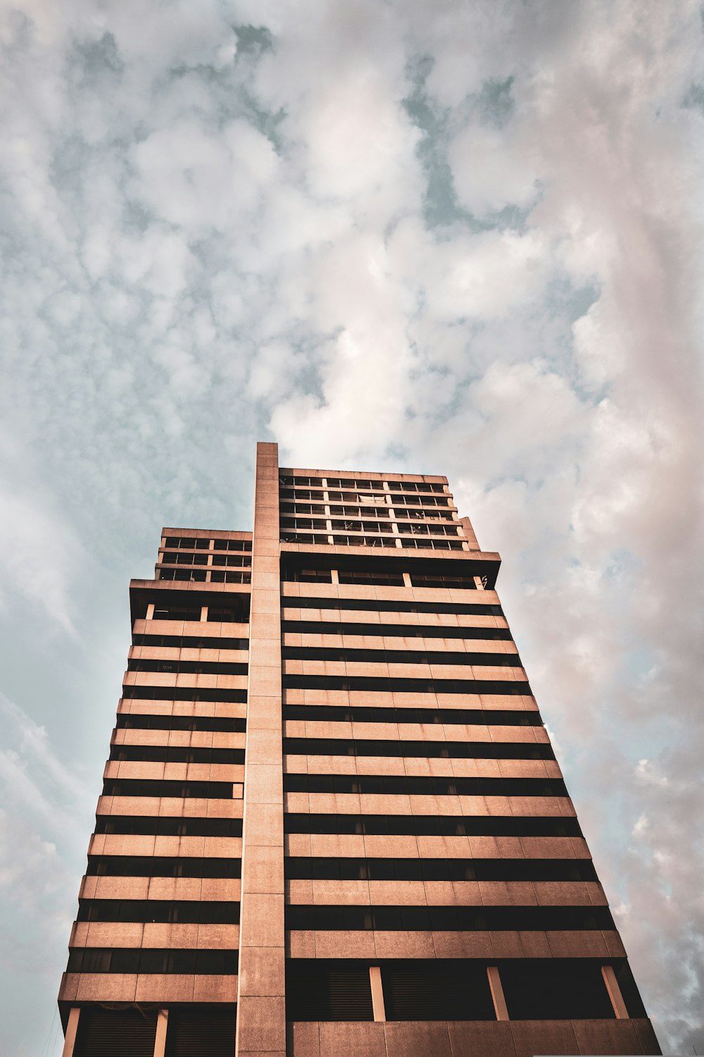 edifício de concreto marrom sob nuvens brancas durante o dia