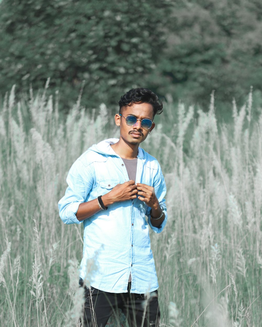 man in white dress shirt wearing black sunglasses standing on grass field during daytime