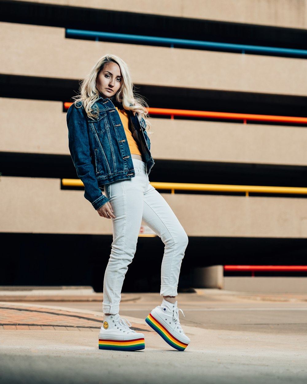 Mujer con chaqueta vaquera azul y pantalones blancos con zapatillas blancas