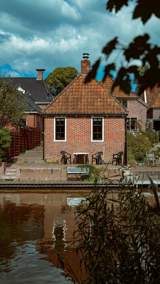 brown brick building beside river during daytime in Winsum Netherlands
