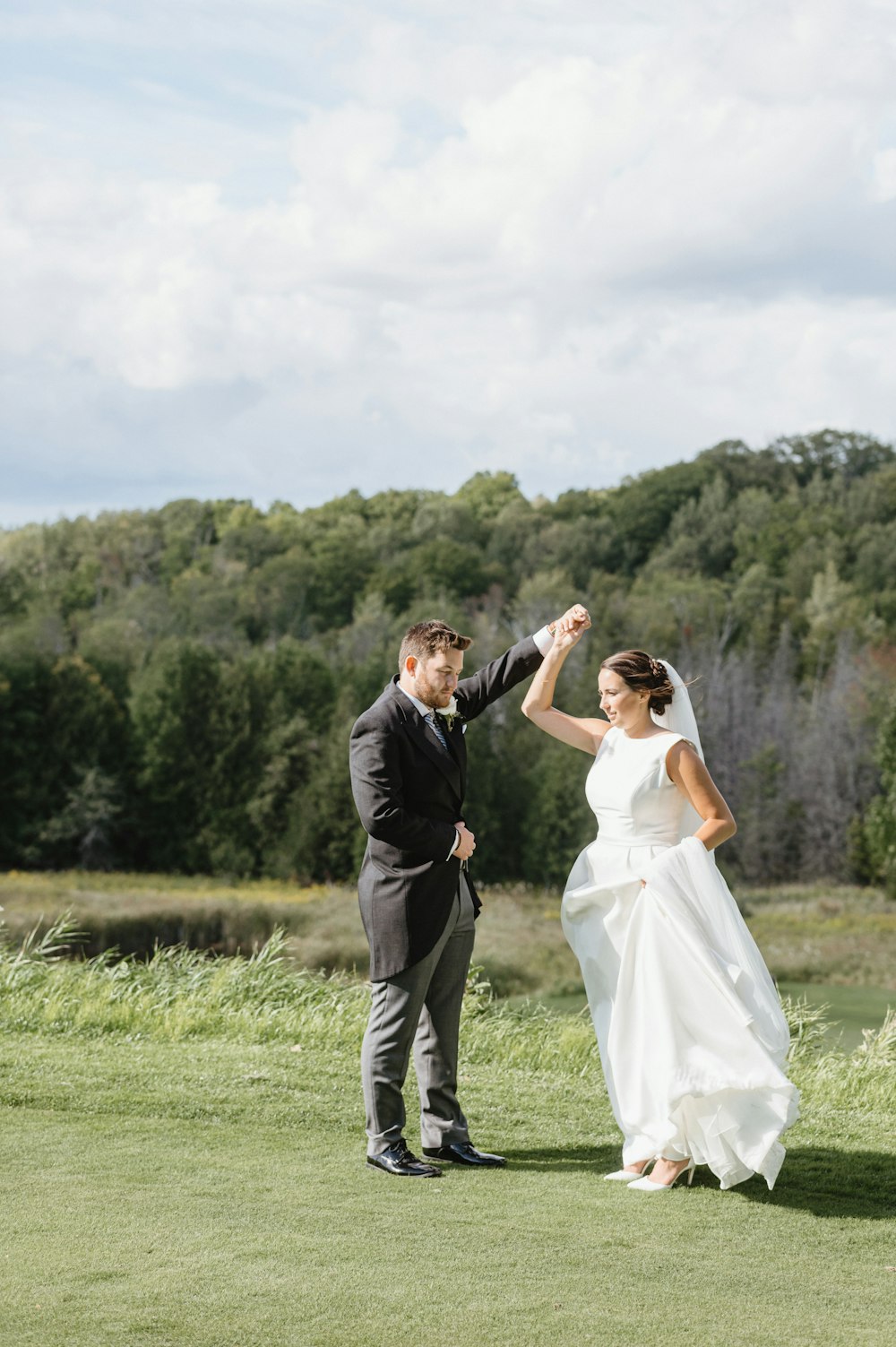 man in black suit kissing woman in white wedding dress on green grass field during daytime