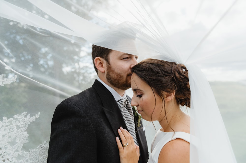 man in black suit kissing woman in white wedding dress