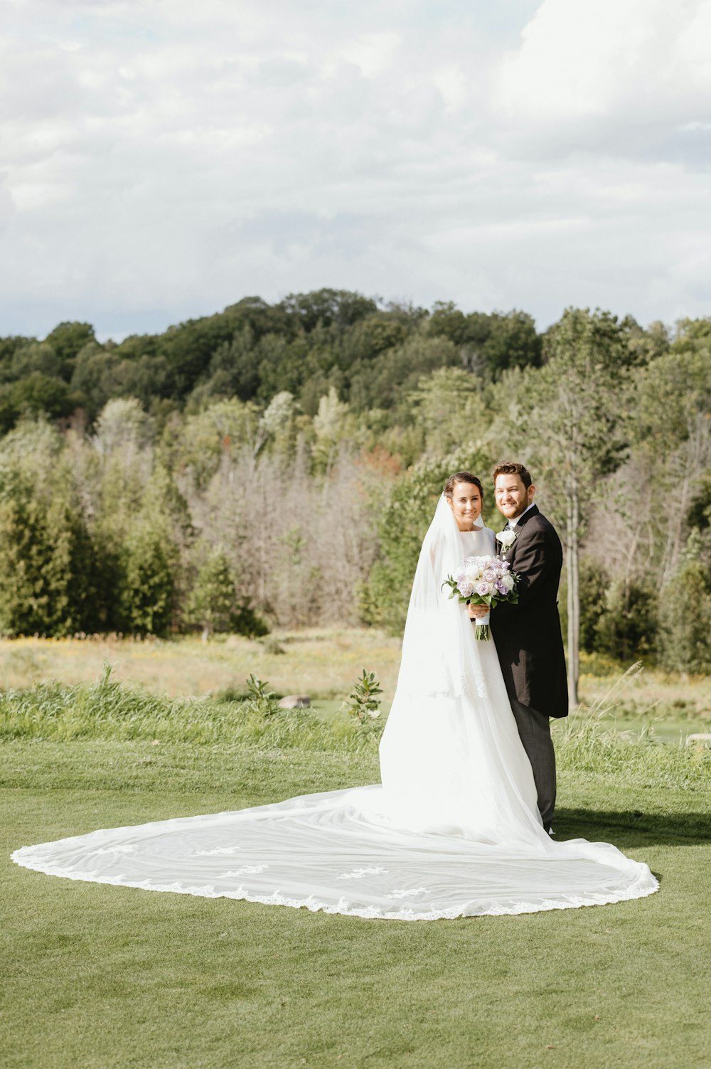 bride and groom standing on green grass field during daytime
