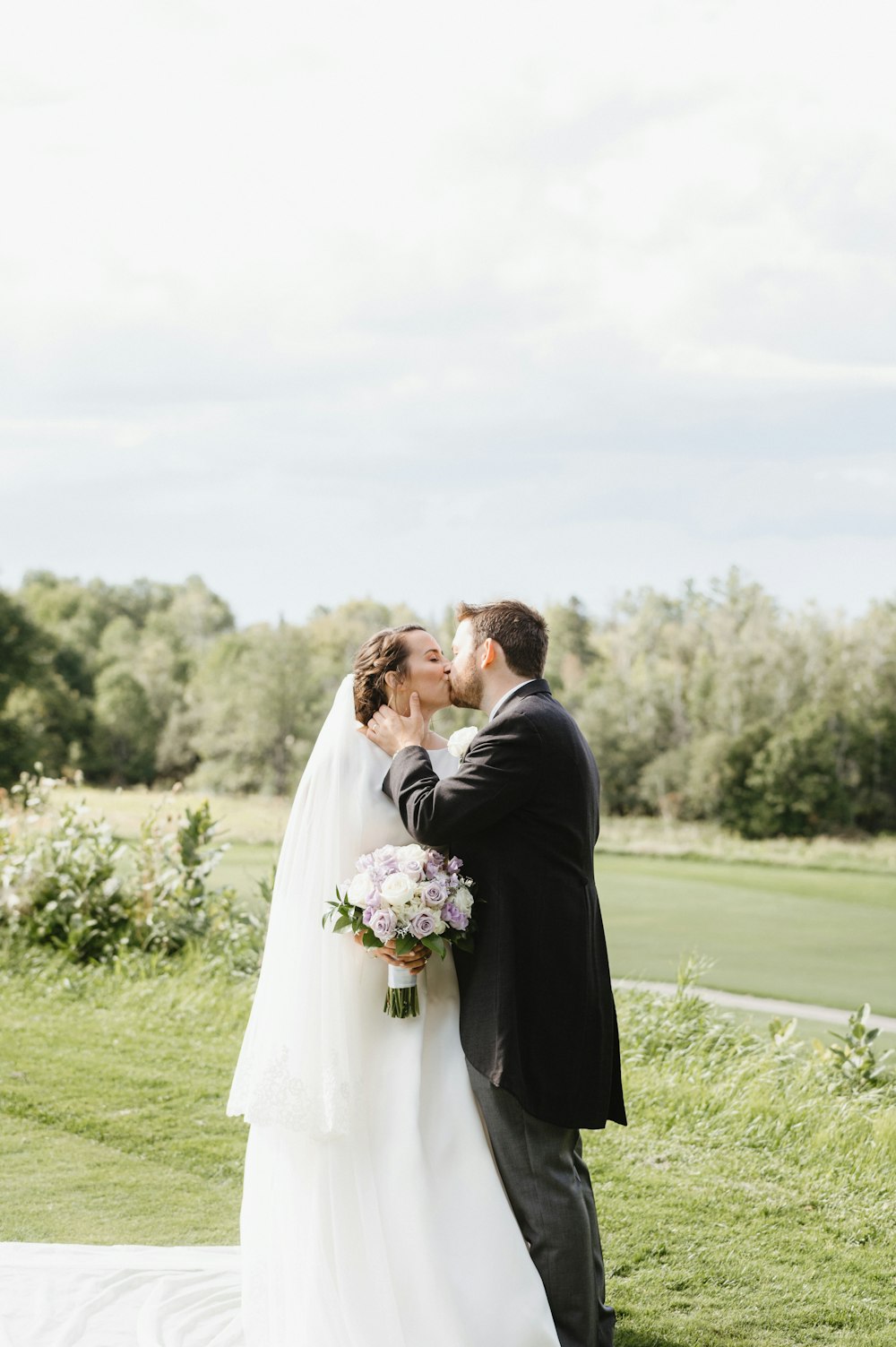 man and woman kissing on green grass field during daytime