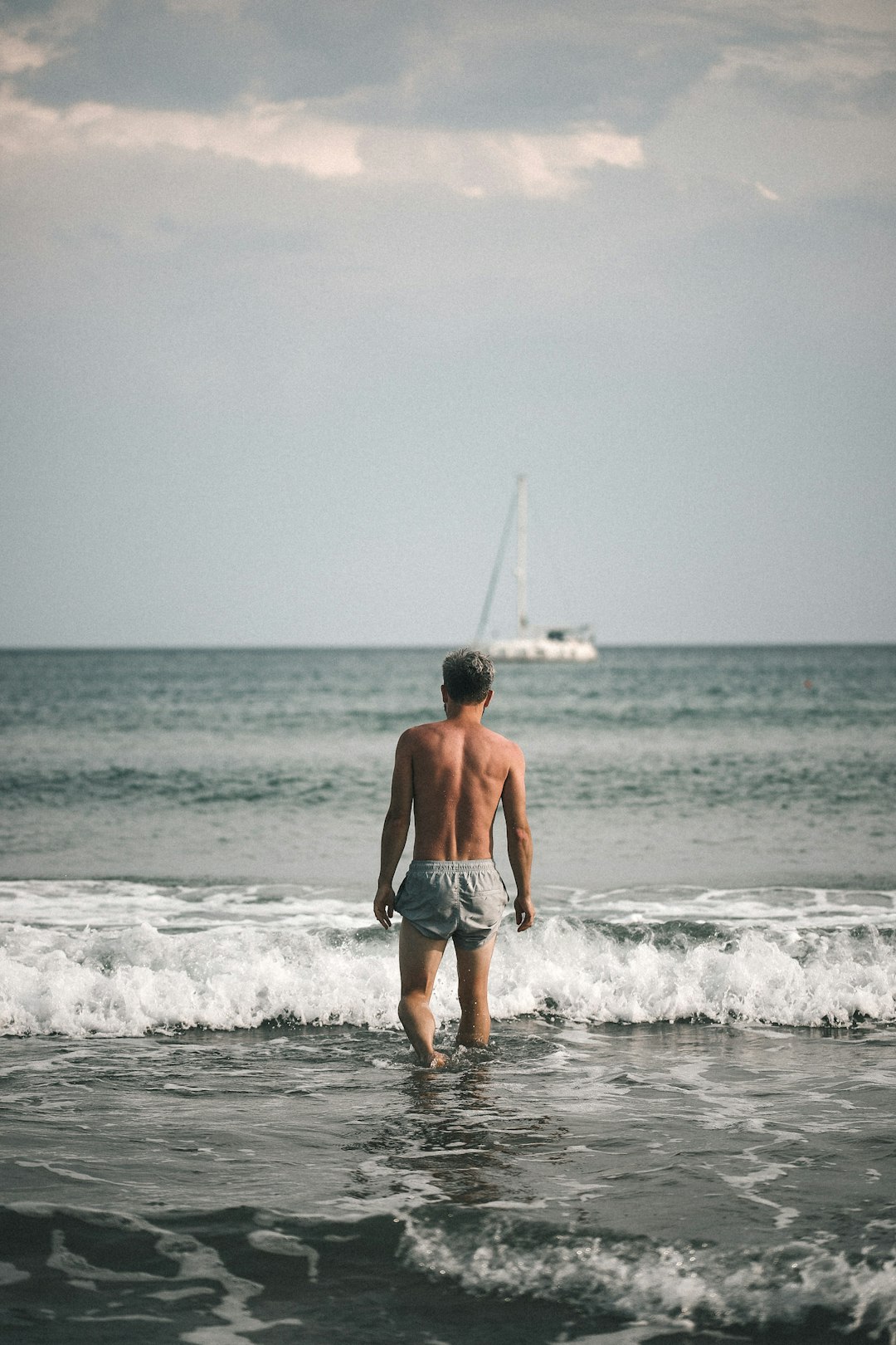 man in blue shorts standing on sea shore during daytime