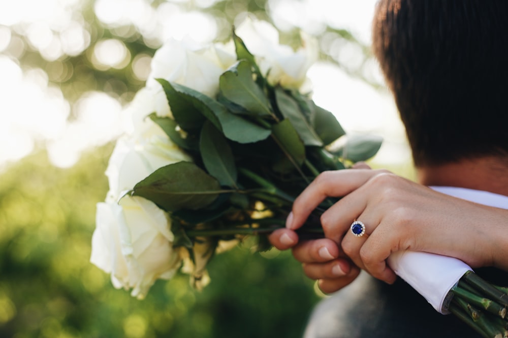 personne tenant une fleur blanche pendant la journée