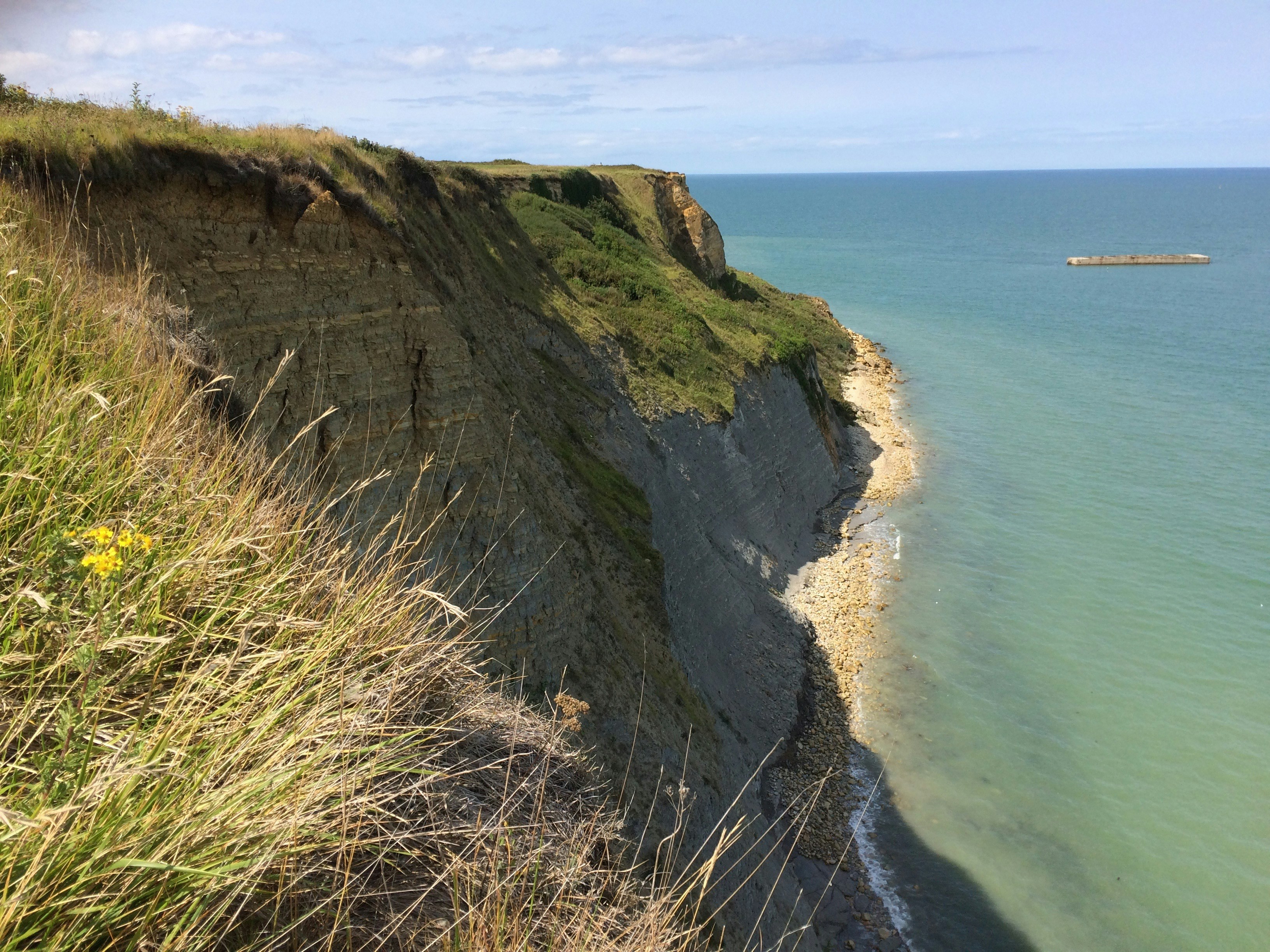 green and brown mountain beside blue sea under blue sky during daytime, A cliff along the coast of Normandy.