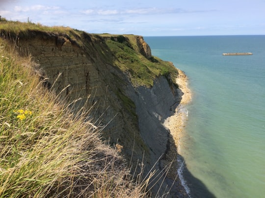 green and brown mountain beside blue sea under blue sky during daytime in Normandy France