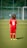 A young child is wearing a red soccer uniform with the number 6 on the back, standing on a green soccer field. The child is facing away towards a goalpost in the distance with a blurred background of a fence and trees.