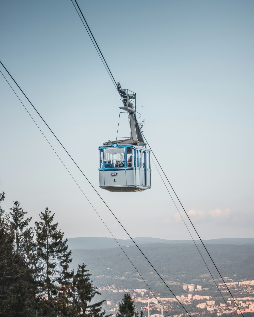 white and blue cable car over green trees during daytime