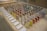 A display of colorful sample panels arranged in a grid on an OSB board table. Each sample is mounted on a wooden block with a variety of colors and textures. Labels with text descriptions are placed in front of the samples. In the background, there is a cardboard box with an IKEA logo.