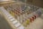 A display of colorful sample panels arranged in a grid on an OSB board table. Each sample is mounted on a wooden block with a variety of colors and textures. Labels with text descriptions are placed in front of the samples. In the background, there is a cardboard box with an IKEA logo.