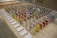 A display of colorful sample panels arranged in a grid on an OSB board table. Each sample is mounted on a wooden block with a variety of colors and textures. Labels with text descriptions are placed in front of the samples. In the background, there is a cardboard box with an IKEA logo.