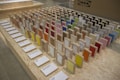 A display of colorful sample panels arranged in a grid on an OSB board table. Each sample is mounted on a wooden block with a variety of colors and textures. Labels with text descriptions are placed in front of the samples. In the background, there is a cardboard box with an IKEA logo.