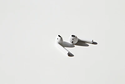 A pair of stylish, noise-cancelling earbuds resting on a minimalist white surface.