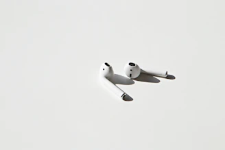 Sleek black wireless earbuds resting on a minimalist white surface with soft shadows