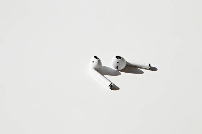 Wireless earbuds resting on a minimalist surface with soft lighting.