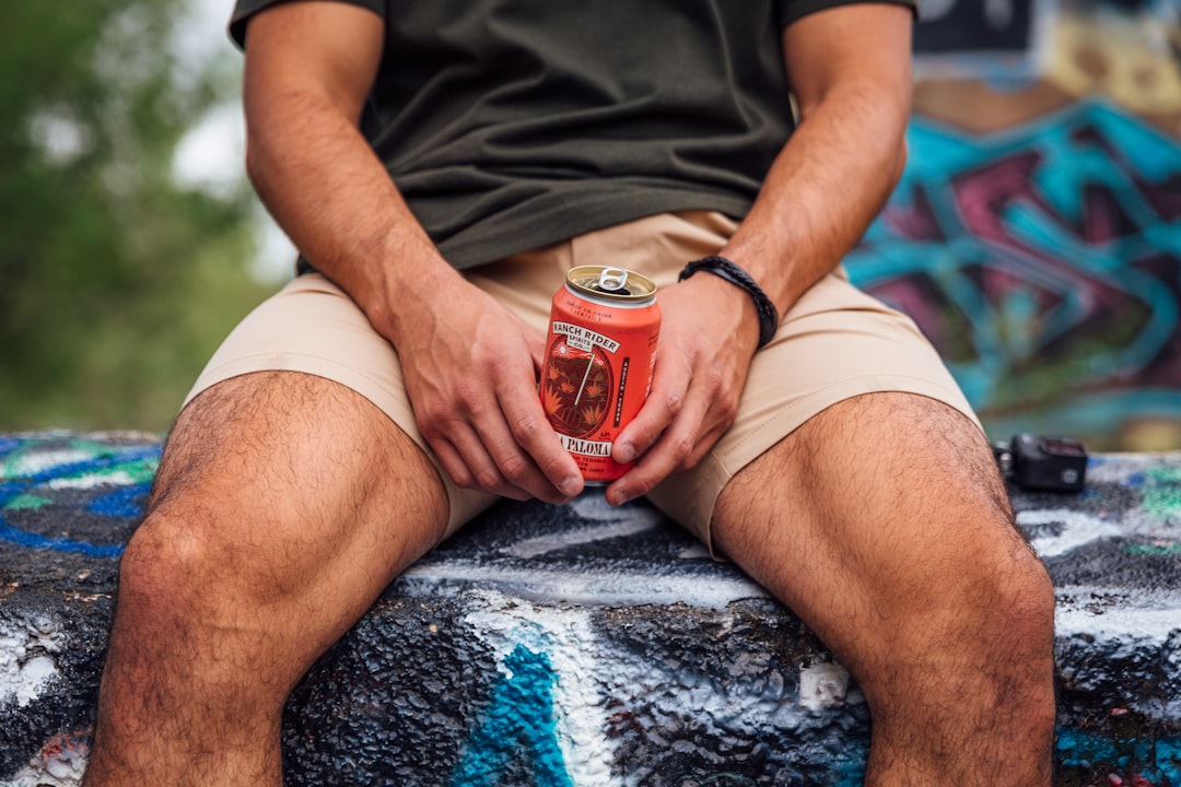 person in black shirt and white shorts holding heinz tomato ketchup