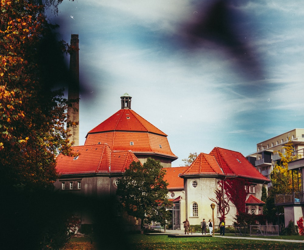 red and white concrete building near green trees under gray sky