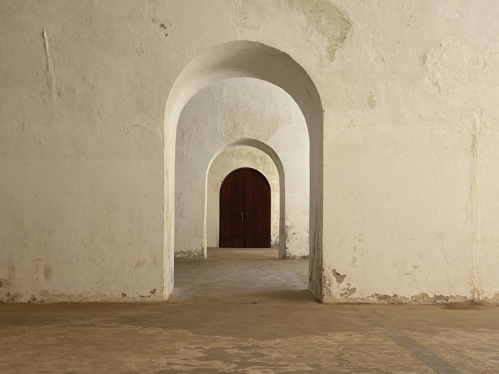 puerta de madera marrón sobre pared de hormigón blanco