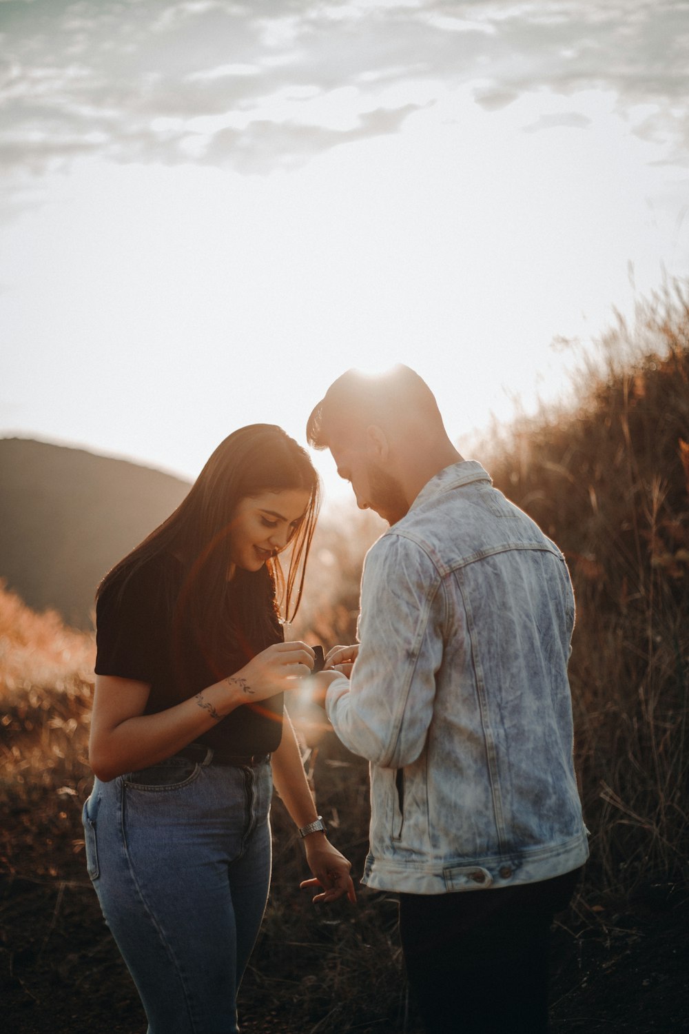 woman in black shirt and blue denim jeans standing beside man in blue denim jacket during