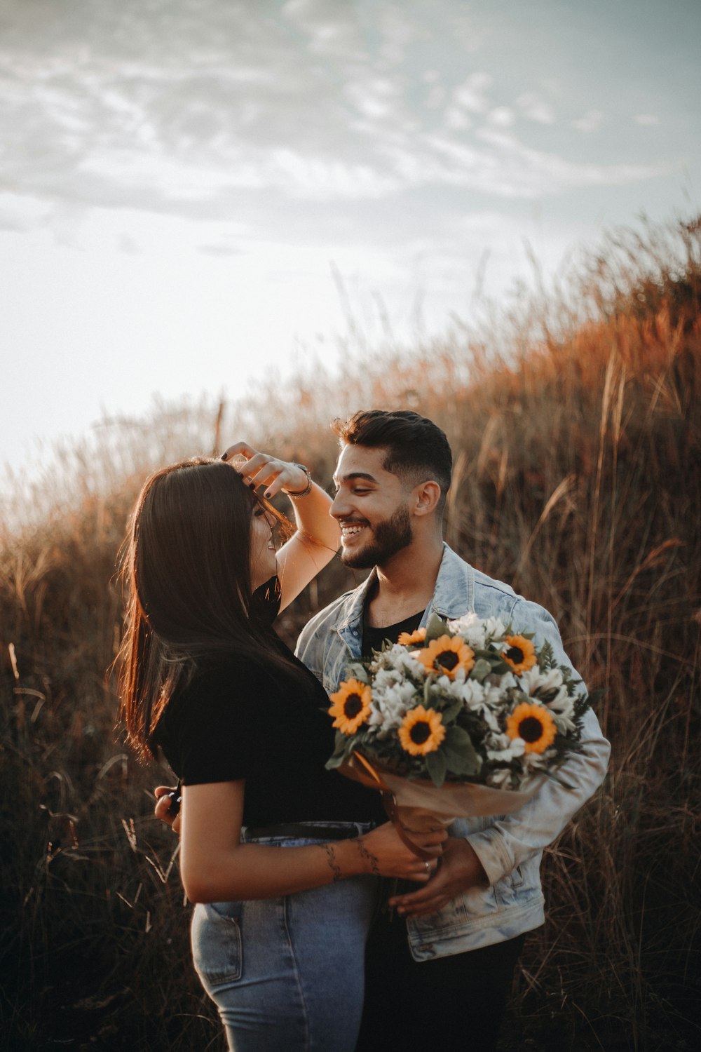 Un homme et une femme s’embrassent sur un champ d’herbe brune pendant la journée