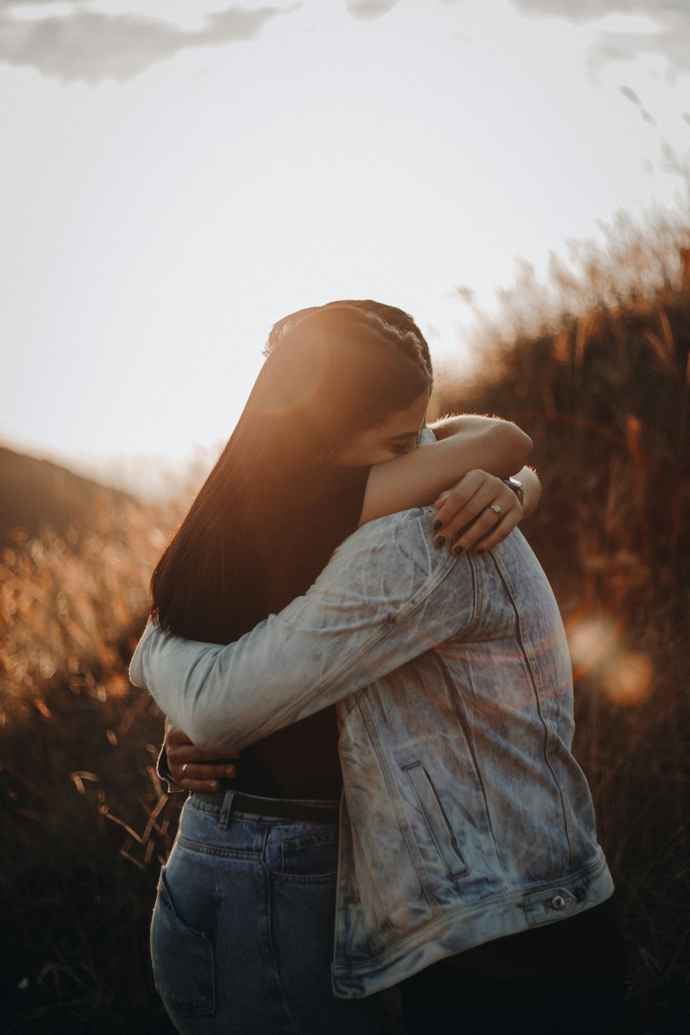 woman in black long sleeve shirt and blue denim jeans covering her face with her hand