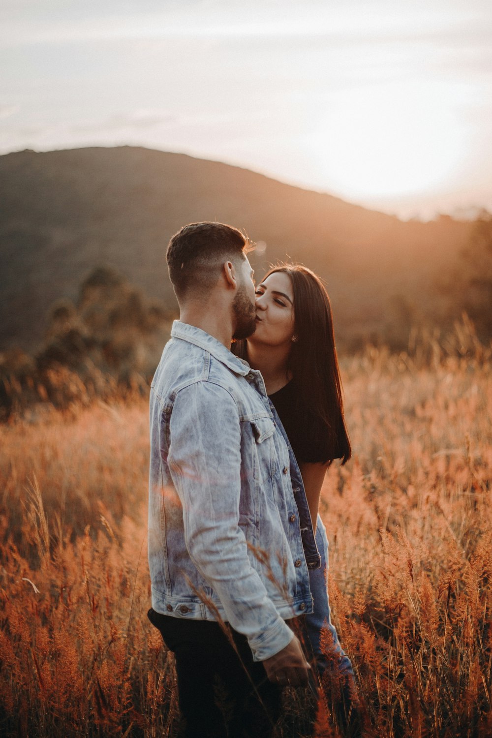 uomo e donna che si baciano sul campo di erba marrone durante il giorno