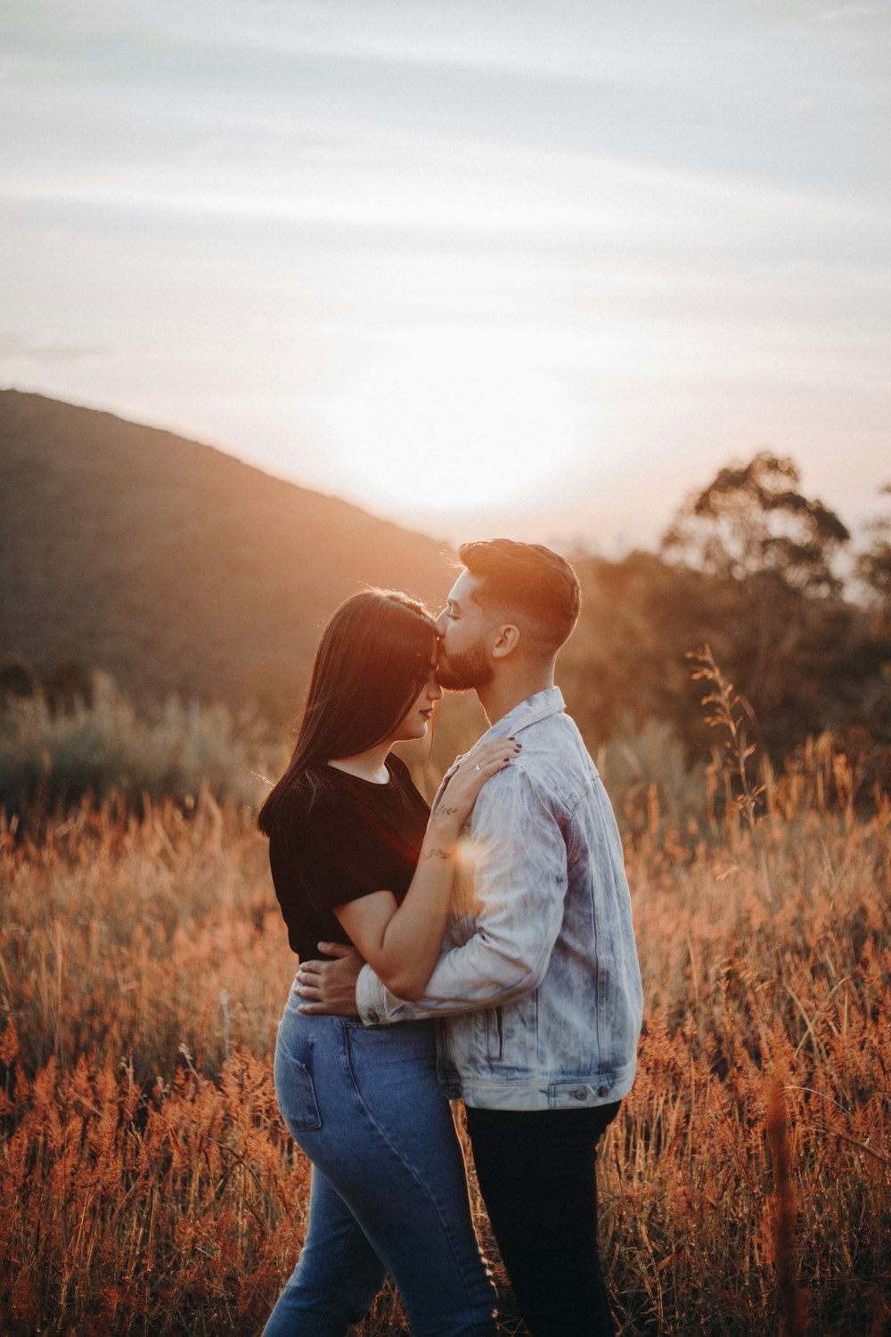 hombre y mujer besándose en el campo de hierba marrón durante el día
