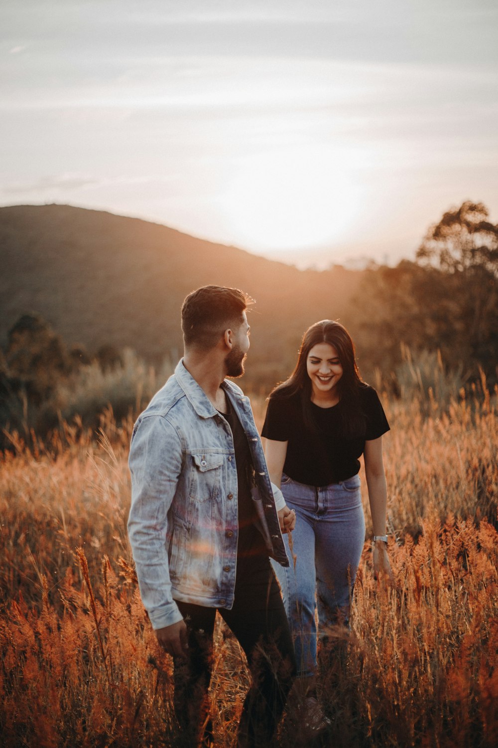 uomo in giacca di jeans blu in piedi accanto alla donna in camicia nera