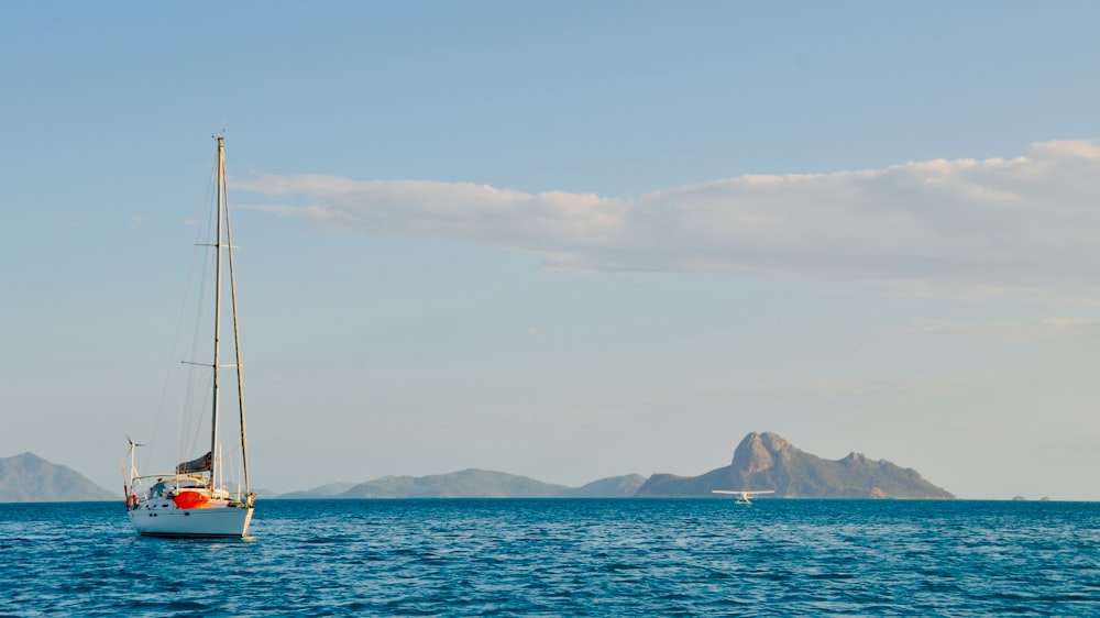 sailboat on sea near mountain during daytime