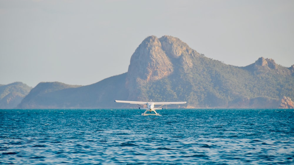 white and red plane on sea near brown mountain during daytime