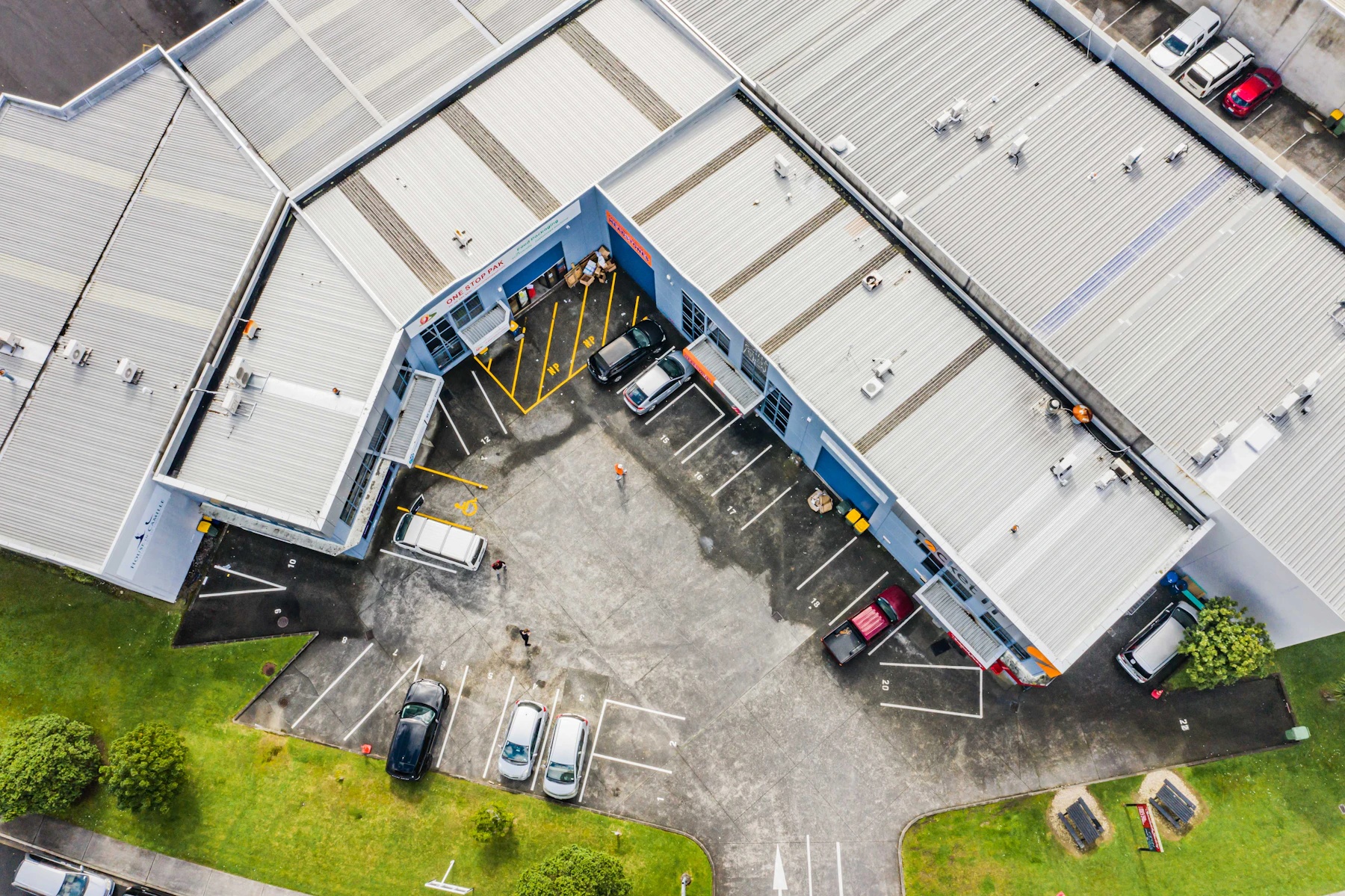 A block of industrial units with roller doors and yard parking, seen from above, in Auckland
