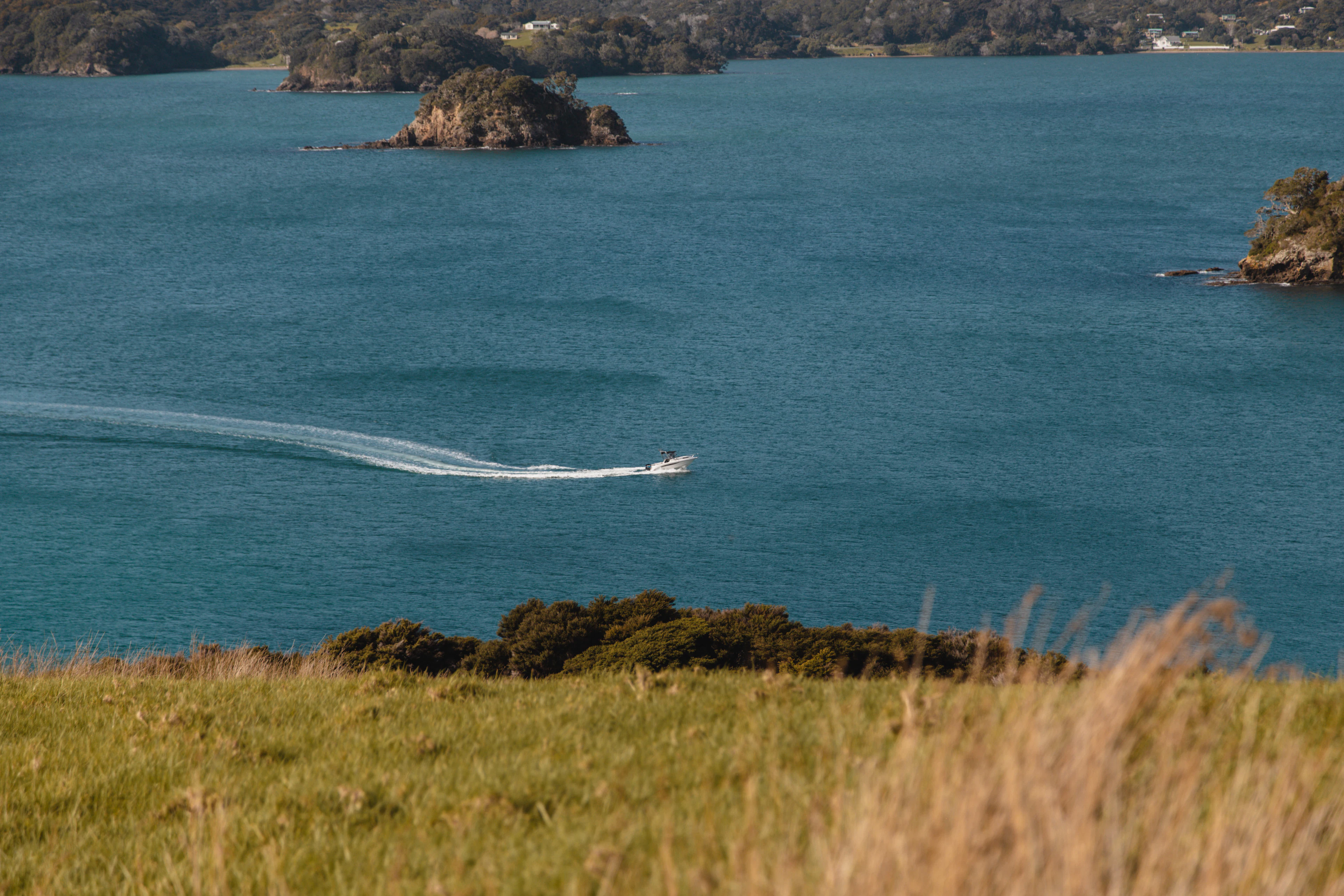 A boat and rocky islets in the Bay of Islands, seen from Urupukapuka Island