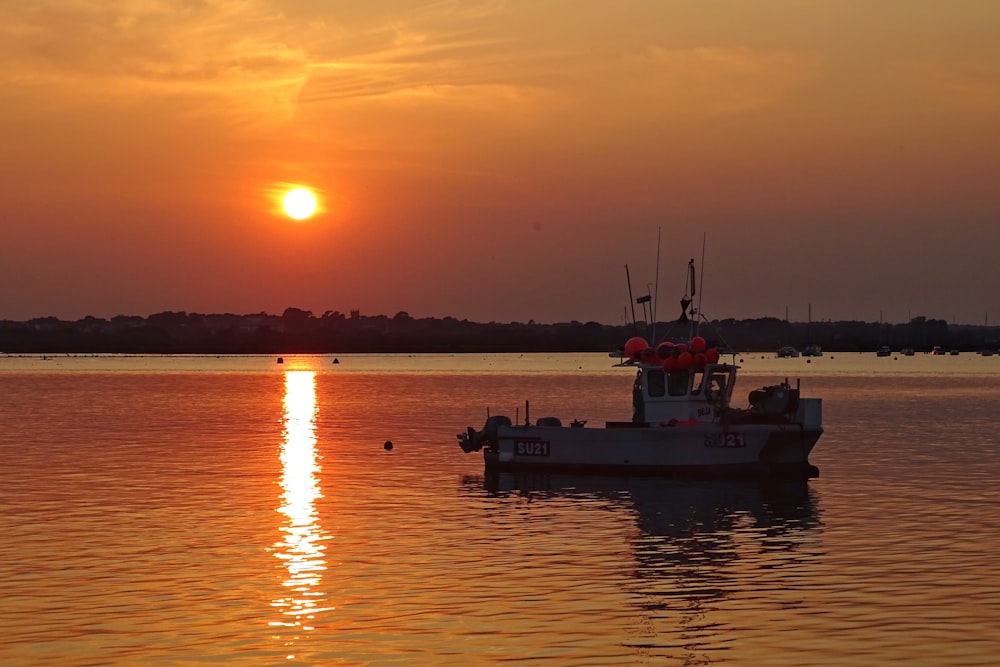 silhouette of boat on sea during sunset