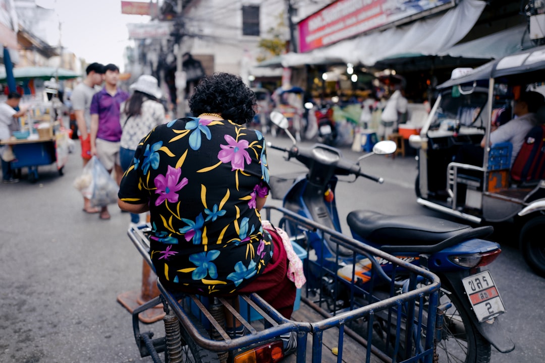 woman in blue and yellow floral shirt sitting on blue shopping cart