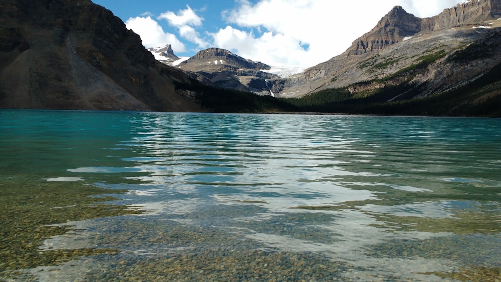 body of water near mountain under blue sky during daytime