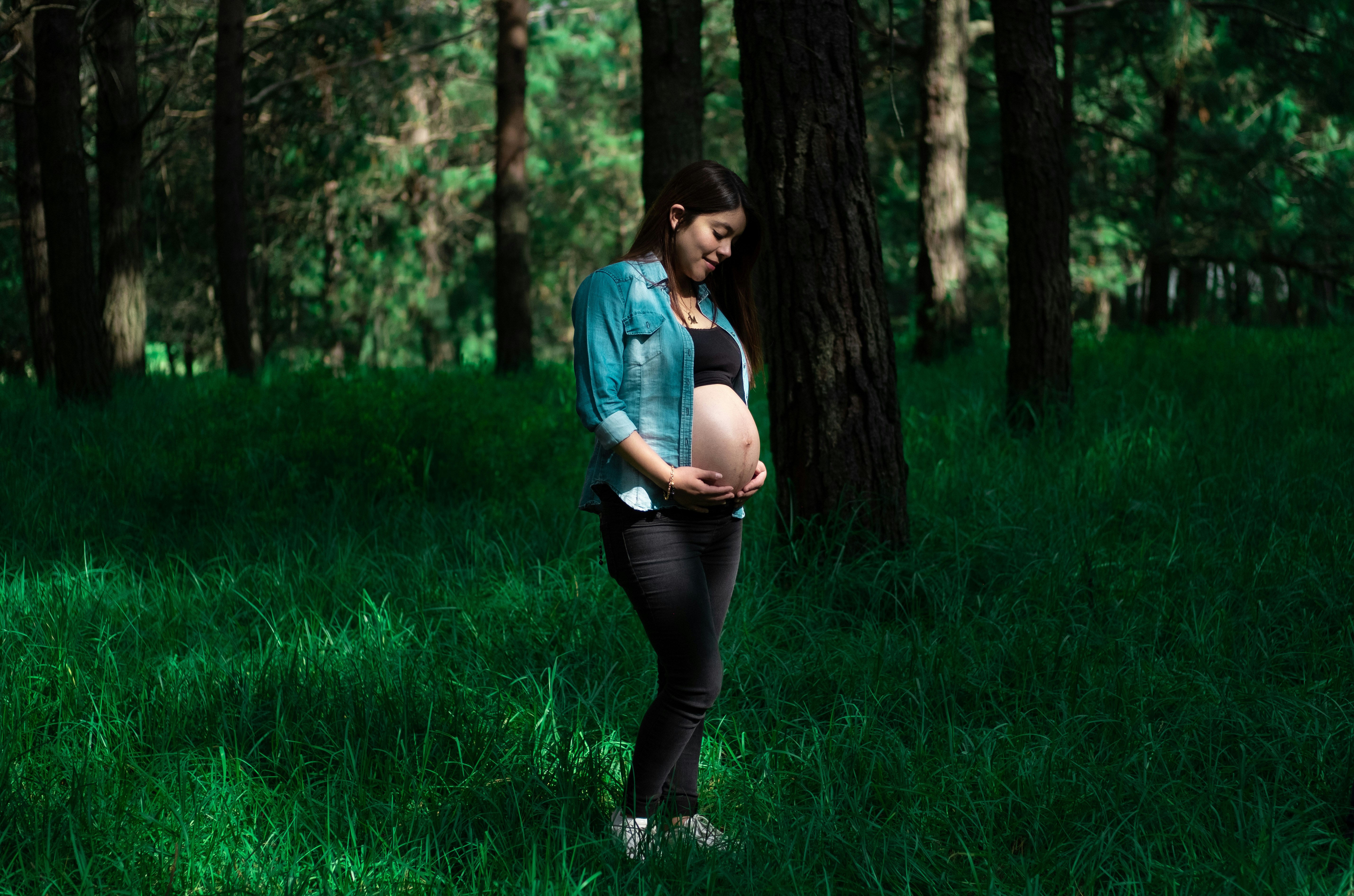 woman in blue denim jacket and black leggings standing on green grass field