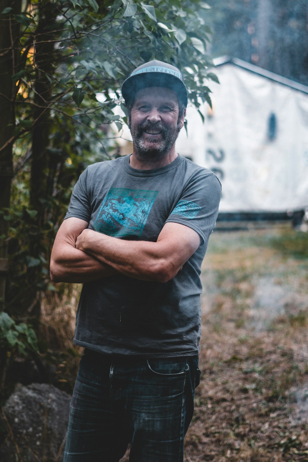 man in gray crew neck t-shirt standing near green trees during daytime