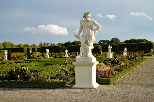 white concrete statue on green grass field during daytime in Herrenhausen Gardens Germany