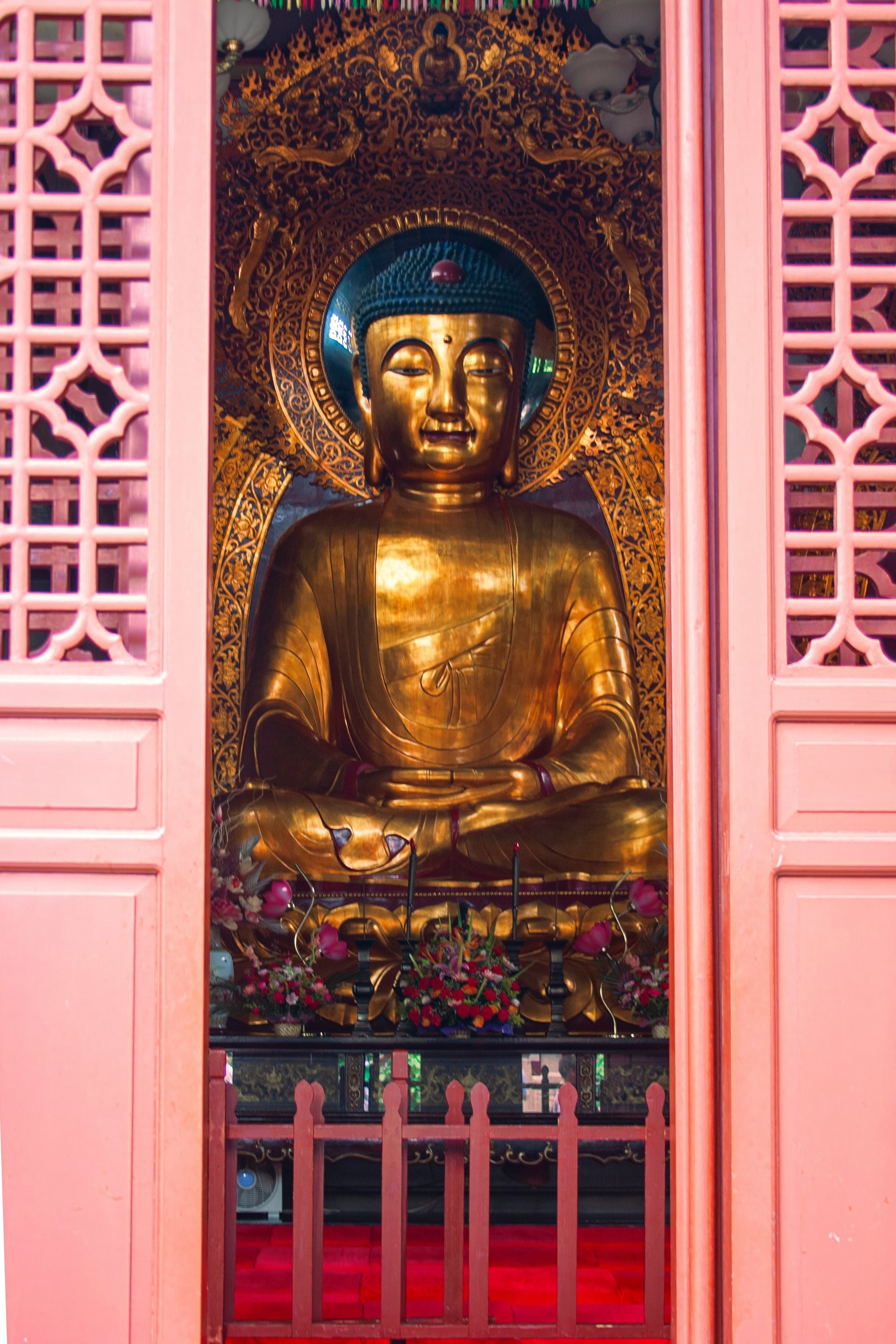 gold buddha statue on red wooden shelf