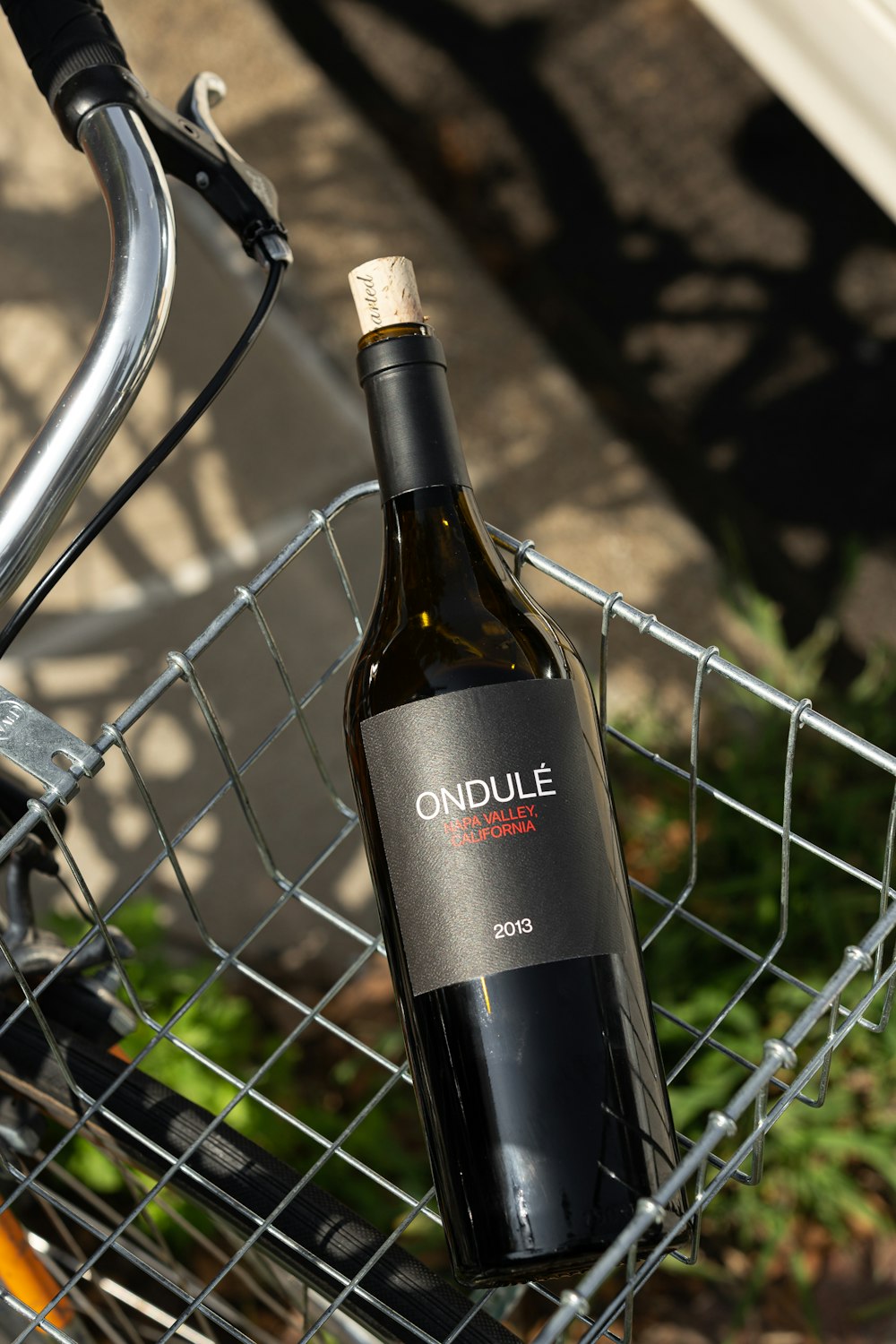 black glass bottle on gray metal fence