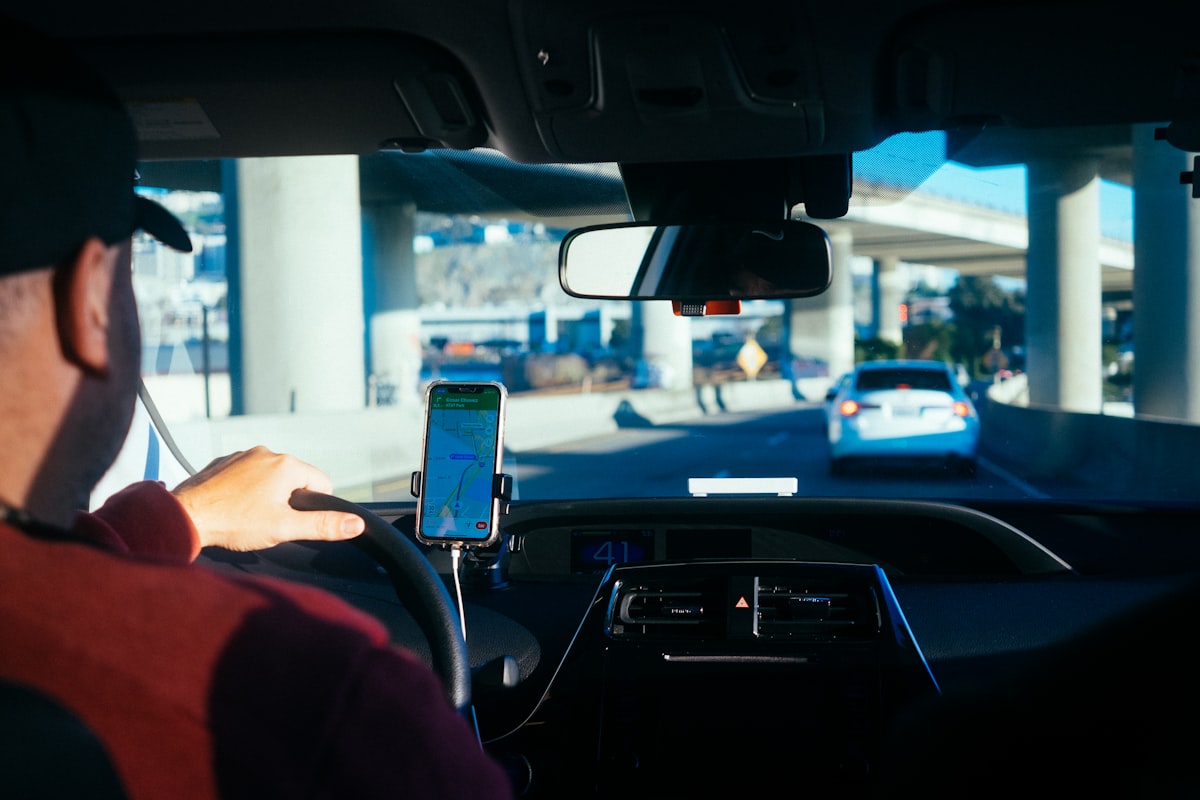 Person using a smartphone inside a rideshare vehicle navigating a city