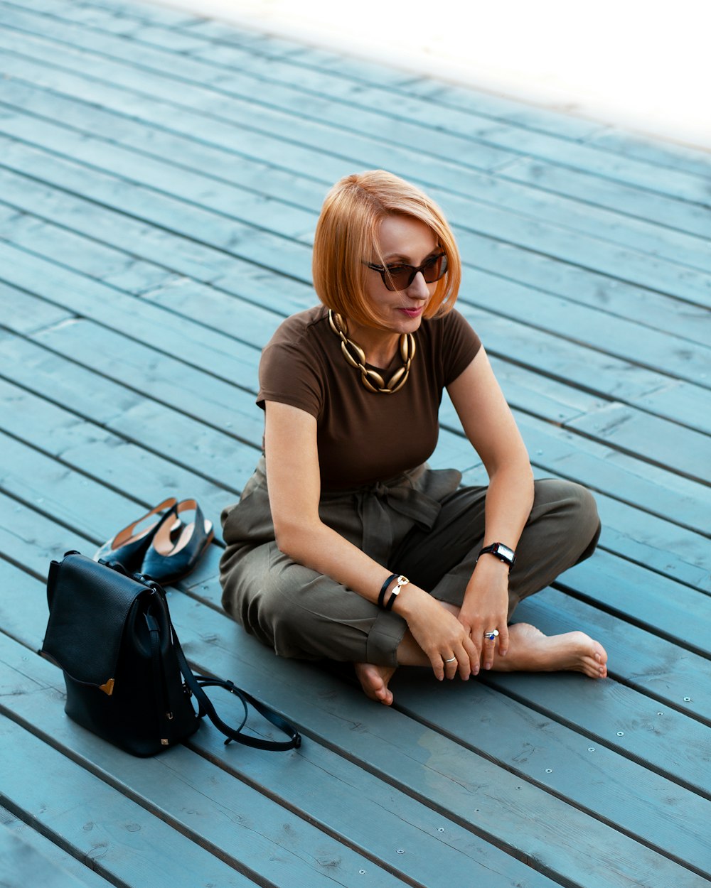 woman in black crew neck t-shirt and gray pants sitting on brown wooden floor