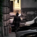 man in black jacket and brown hat standing beside black car during daytime