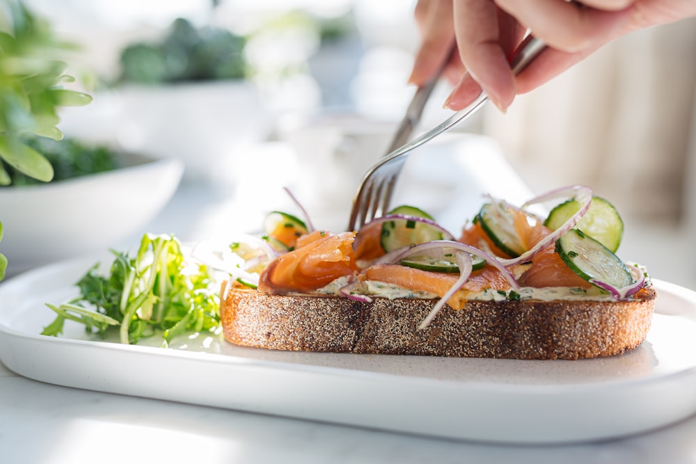 person holding stainless steel fork and knife slicing food