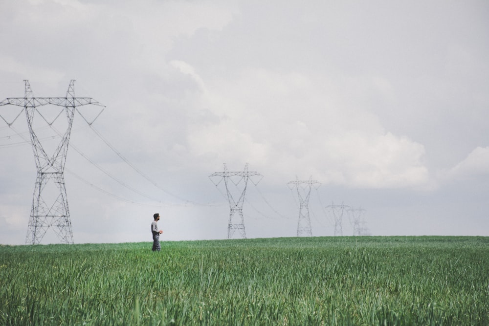 person in black jacket walking on green grass field during daytime