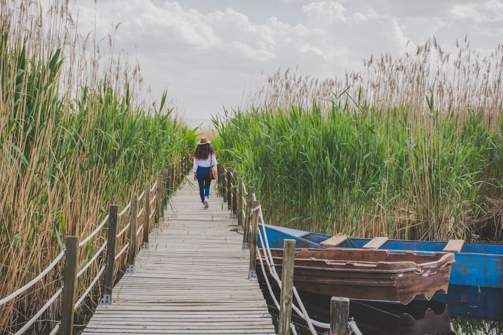 woman in blue denim jacket walking on wooden dock during daytime