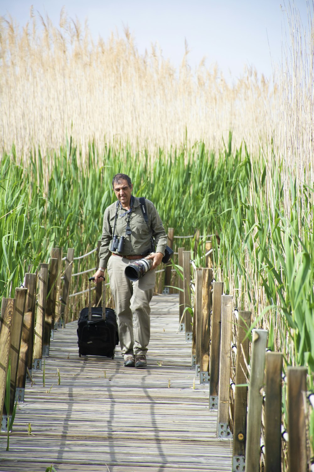 man in gray jacket and black pants sitting on wooden dock during daytime