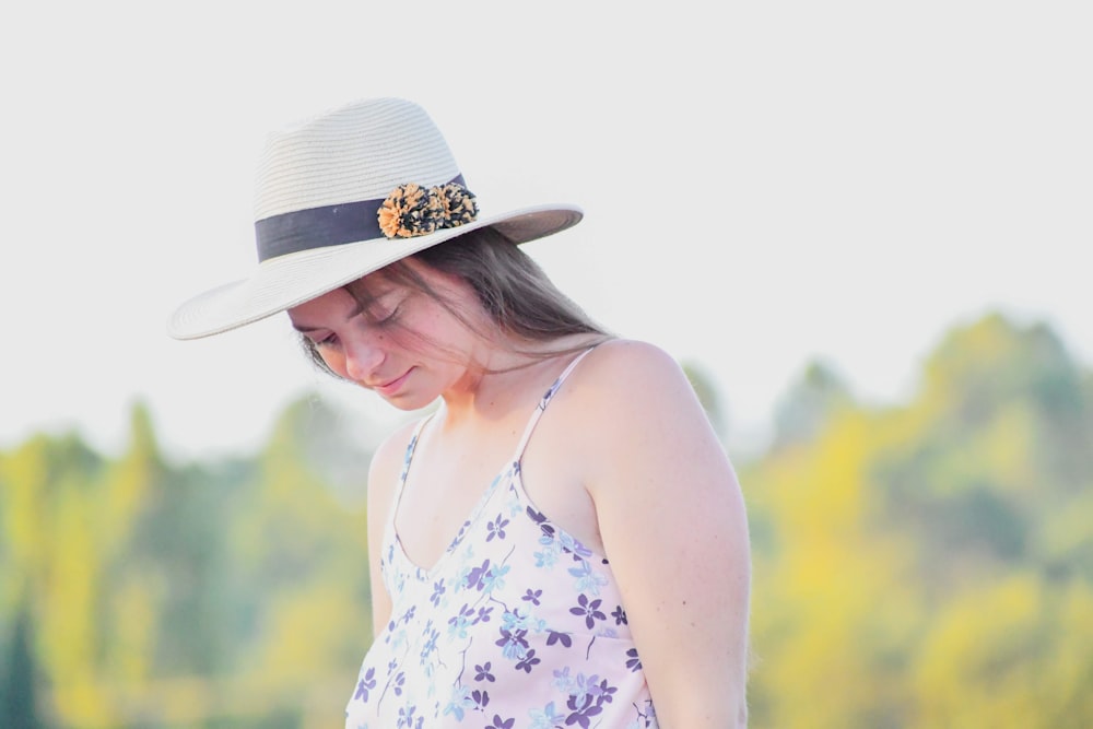 woman in white and blue floral tank top wearing white sun hat